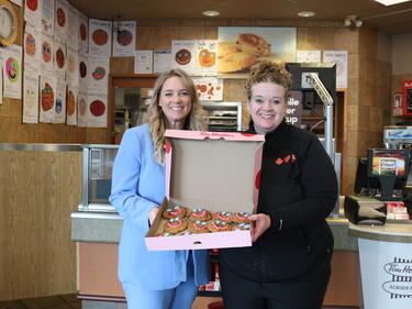 two women smiling holding a box of cookies