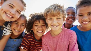 Close up of pre-teen friends in a park smiling to camera